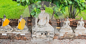 Row of Buddhas under breadfruit tree. Medieval Buddhist temple Wat Yai Chai Mongkhon in Ayutthaya