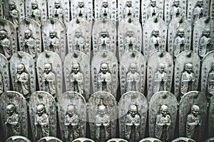 Row of Buddhist Jizo statues in a temple in Japan with hieroglyphs on them