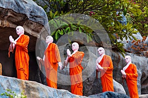 Row of Buddhist Monk statues in orange monastic robes