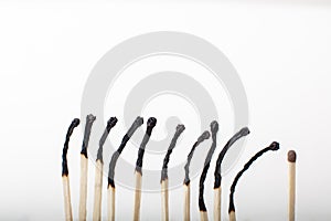 Row of burnt matches with one unused one