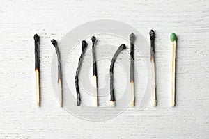 Row of burnt matches and whole one on wooden background. Uniqueness concept