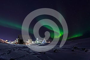 Row of cabins and green Northern lights in suburb of Nuuk