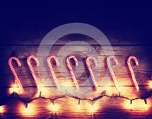 A row of candy canes and christmas lights toned with a retro vintage instagram filter effect