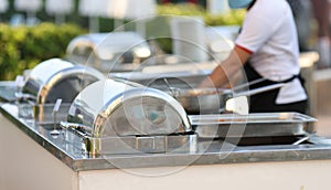 Row of chafing dishes closeup. Cooked meat vegetables and garnish are on large baking sheet