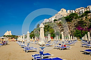 Row of Chaise lounge and beach umbrellas on a beach with a fabulous view to Sperlonga