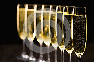 A row of champagne glasses on a black background. Selective foc