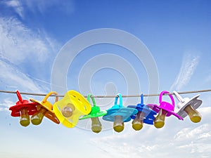 Row of child pacifier, soother and baby dummies on rope