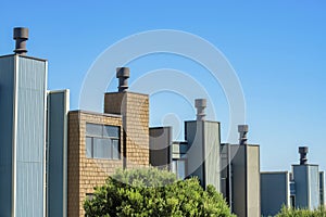 Row of chimneys with visible windows and front yard trees with blue and white sky in the historic districts of san