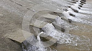 Row of chute dentate blocks in concrete water spillway channel slope slowing down the flow of water running down