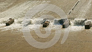 Row of chute dentate blocks in concrete water spillway channel slope slowing down the flow of water running down