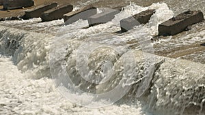 Row of chute dentate blocks in concrete water spillway channel slope slowing down the flow of water running down