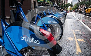 A row of Citibikes on a New York City street on a rainy day.