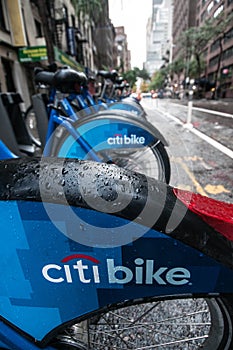 A row of Citibikes on a New York City street on a rainy day.