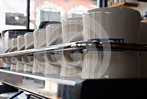 Row of Clean Coffee Mugs Behind a Chrome Rail