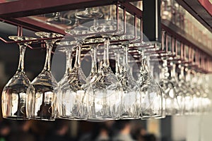 A row of clean empty wine glasses hang