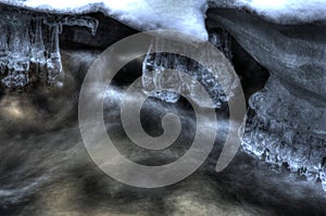 Row of clean transparent icicles hanging in cold forest creek water flow