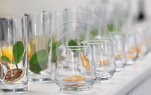 row of clear empty glasses with dehydrated fruits ready to be filled with drinks for a function