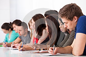 Row of college students writing at desk