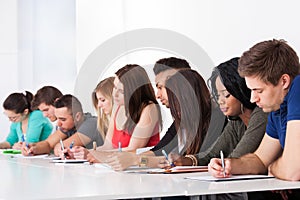 Row of college students writing at desk