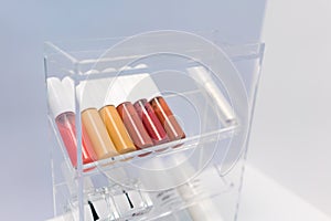 A row of color lipsticks and nail coating on transparent acrylic