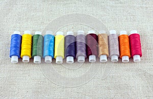 Row of colored spools with threads closeup