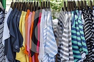 Row of colorful Apparel on Shoulders Hangers of Gondola of Retail Shop with other Items on Background