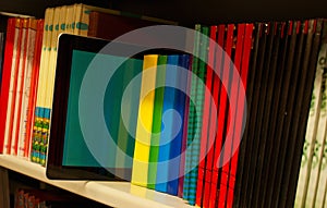 Row of colorful books and electronic book reader photo