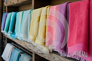 row of colorful hammam towels on wooden shelf