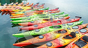 Row of colorful kayaks for rent in the water