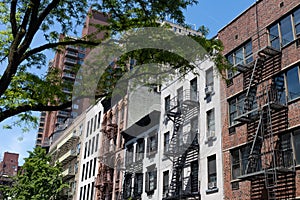 Row of Colorful Old Buildings with Fire Escapes on the Upper East Side of New York City with Green Trees