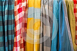 Row of colorful soft cotton fabric scarfs in plain and checker pattern selling in local shop