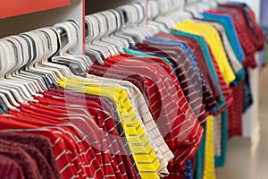 Row of colorful T shirts on hangers. Fashion retail shop display.