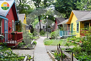 A row of colorful tiny houses, each with its own garden and walkway leading to the entrance. Ai generated