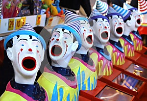 A row of colourful toy clowns with open mouths, an attraction at a fair