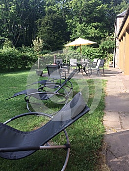 A row of comfortable lounge chairs stand in the garden in perspective on the grass as a place of rest