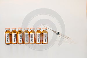 Row of coronavirus covid-19 vaccine vials and medical syringe with needle up on white background. Vaccination concept. Advertising