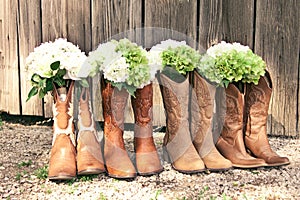 Row of cowboy boots and bouquets at a country theme wedding