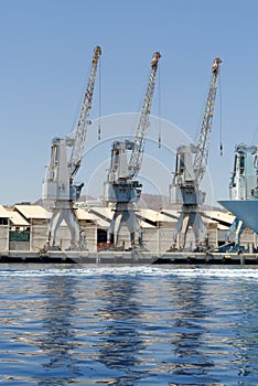 Row of cranes and their reflections in the sea in Eilat harbor