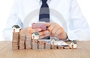 A row of declining dollar coins and a person using a mobile phone