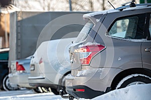 Row of different cars parked  in the outdoor parking on a snowy winter day