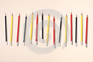 Row of different colors pencils on a beige paper background with copy space for your text