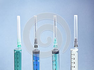 Row of different disposable syringes on blue background