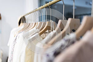 Row of different female clothes hanging on rack in hipster fashion show room in shopping mall. Trendy women wear