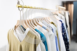 Row of different female clothes hanging on rack in hipster fashion show room in shopping mall. Trendy women wear