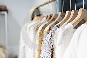 Row of different female clothes hanging on rack in hipster fashion show room in shopping mall. Trendy women wear