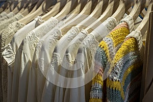 Row of different female clothes hanging on rack in hipster fashion show room in shopping mall. Trendy women wear