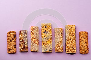 Row of different granola bars on violet background