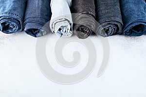 Row of different rolled jeans on white background