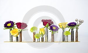 Row of Multicolored Flowers in Old Bullet Casings on White Background photo