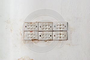 Row of Dirty Light Switches on Stained Concrete Wall